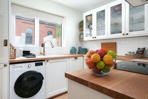 Una cocina moderna con lavadora, frutero en la encimera y alacenas arriba.