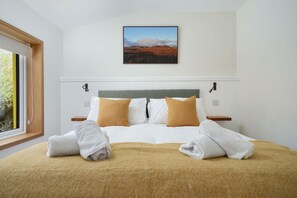 Un cuarto de hotel con una cama, una ventana, un cuadro en la pared y vistas al exterior.
