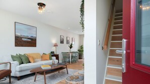 Een moderne woonkamer met een bank, salontafel en een eethoek met stoelen.
