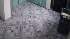 Une cuisine avec des armoires de couleur turquoise, un réfrigérateur noir et des carreaux de sol à motifs.