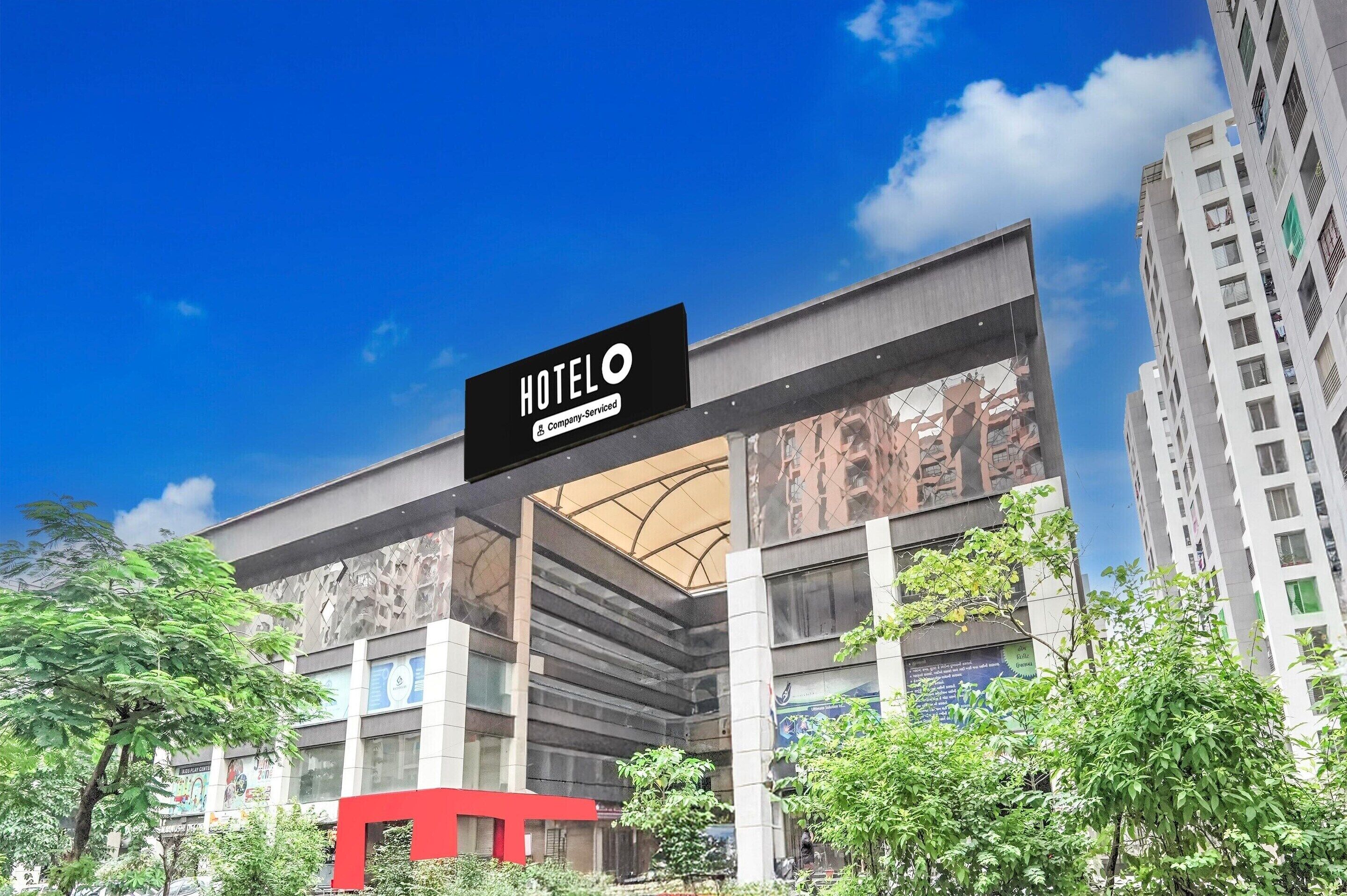 A modern hotel building with a prominent sign indicating it is a company-serviced hotel.