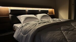 A neatly made bed with a headboard, a bedside table, and a wall-mounted light. - ALSAWAH 3BR Garden Apartment - New Cairo (New Cairo)