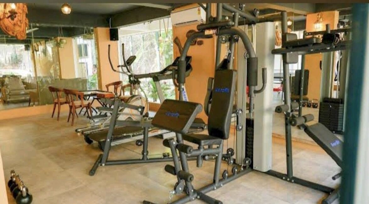 Uma academia com equipamentos de ginástica, um banco e uma esteira.