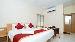 Ein Hotelzimmer mit einem Bett, einem Schreibtisch, einem Stuhl, einem Kleiderschrank und einer Klimaanlage.
