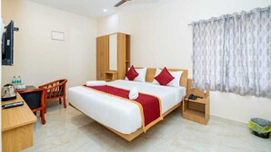 Ein Hotelzimmer mit einem Bett, einem Schreibtisch, einem Stuhl, einem Deckenventilator und einem Fenster mit Vorhängen.