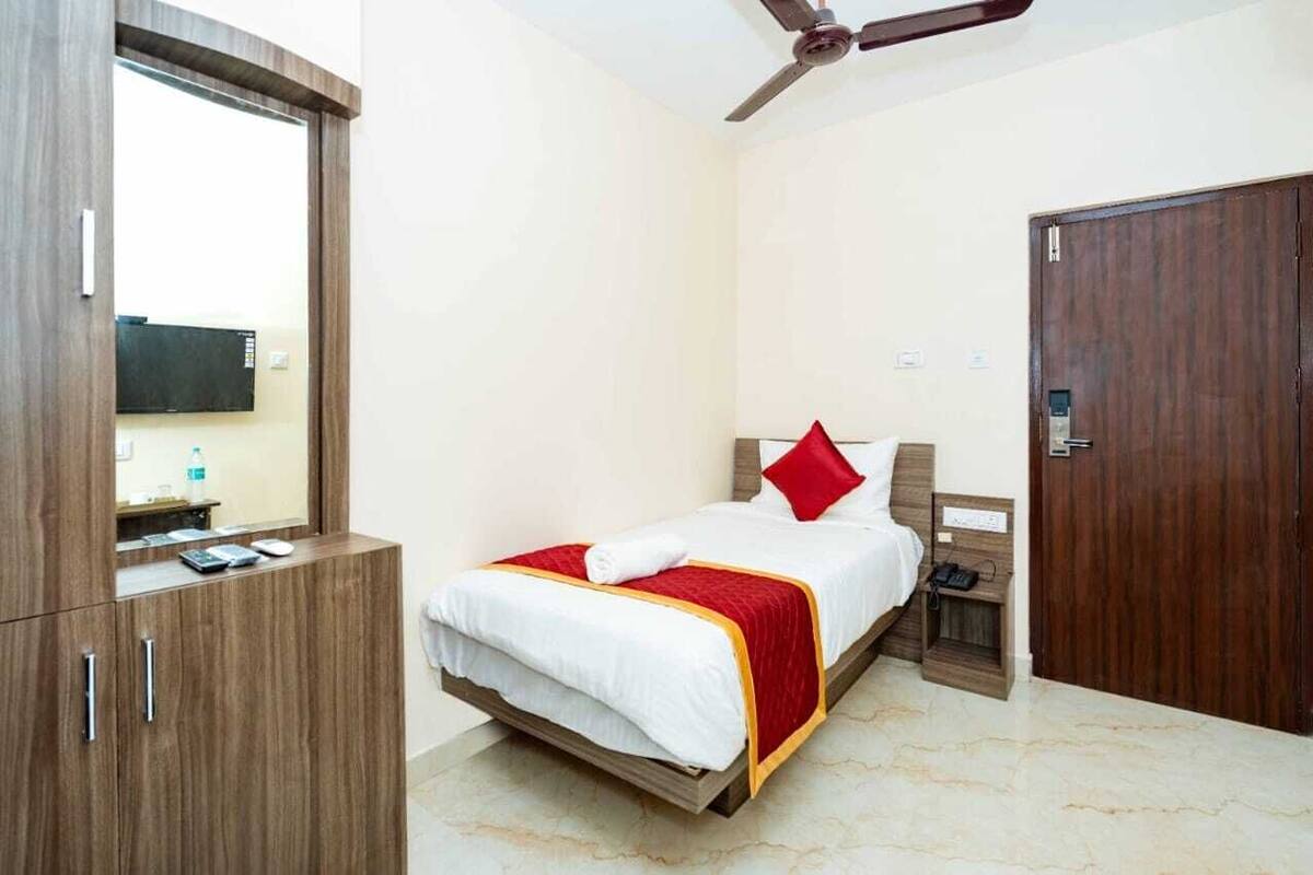 A hotel room with a bed, a wardrobe, a desk with a computer, and a door.
