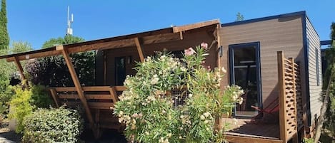 A modern cabin with a wooden deck, a covered porch, and a small garden area.