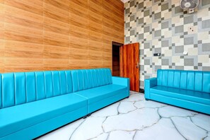 Ein Zimmer mit zwei blauen Sofas, einer Holzvertäfelung, einer Wand mit Muster und einem Marmorboden.