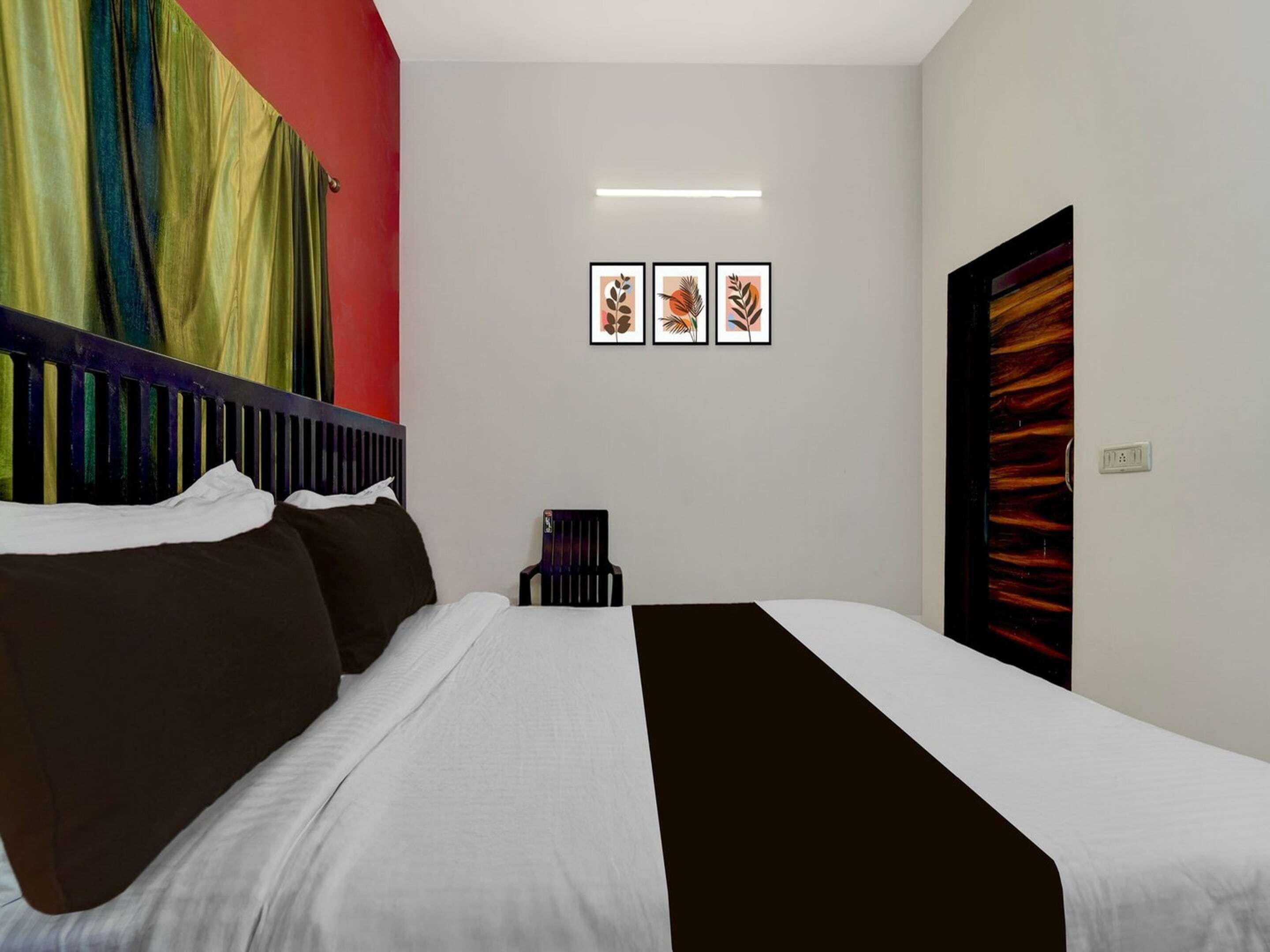 A hotel room with a bed, a chair, and a wall with three framed pictures.