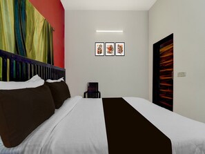 Ein Hotelzimmer mit einem Bett, einem Sessel und einer Wand mit drei Bildern in Rahmen.