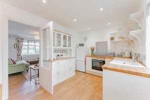 A modern kitchen with white cabinetry, a wooden countertop, and a built-in oven.