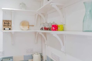 Eine Küche mit weißen Schränken, einem Holzschild, einem Nudelholz und Gläsern in den Regalen.