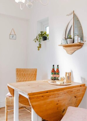 A dining area with a wooden table, wicker chairs, and a hanging plant.