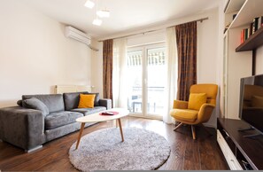 Una sala de estar con sofá, sillón, televisor y una mesita.