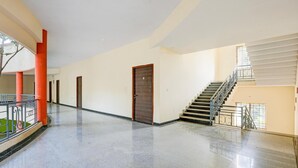 A spacious indoor area with a staircase, a door, and a railing. - Super Townhouse City Center Ernakulam (Kanayannur)
