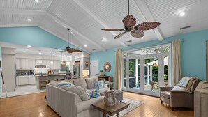 A spacious living area with a sofa, a coffee table, and a dining area with a kitchen in the background.