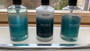 Trois bouteilles de produits de bain à base d’algues marines sont posées sur un rebord de fenêtre.
