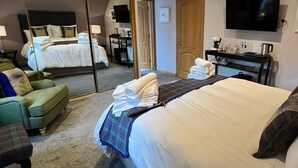 Une chambre d’hôtel équipée d’un lit, d’un canapé, d’un bureau, d’une télévision et d’un miroir.