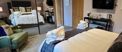 A hotel room with a bed, a sofa, a desk, a television, and a mirror.