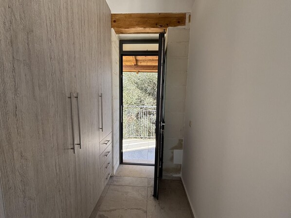 A narrow hallway with a wooden ceiling beam, a sliding door leading to an outdoor balcony, and a concrete floor. - MayaElisa Villa with Heated Pool, By Hellocrete (Vamos)