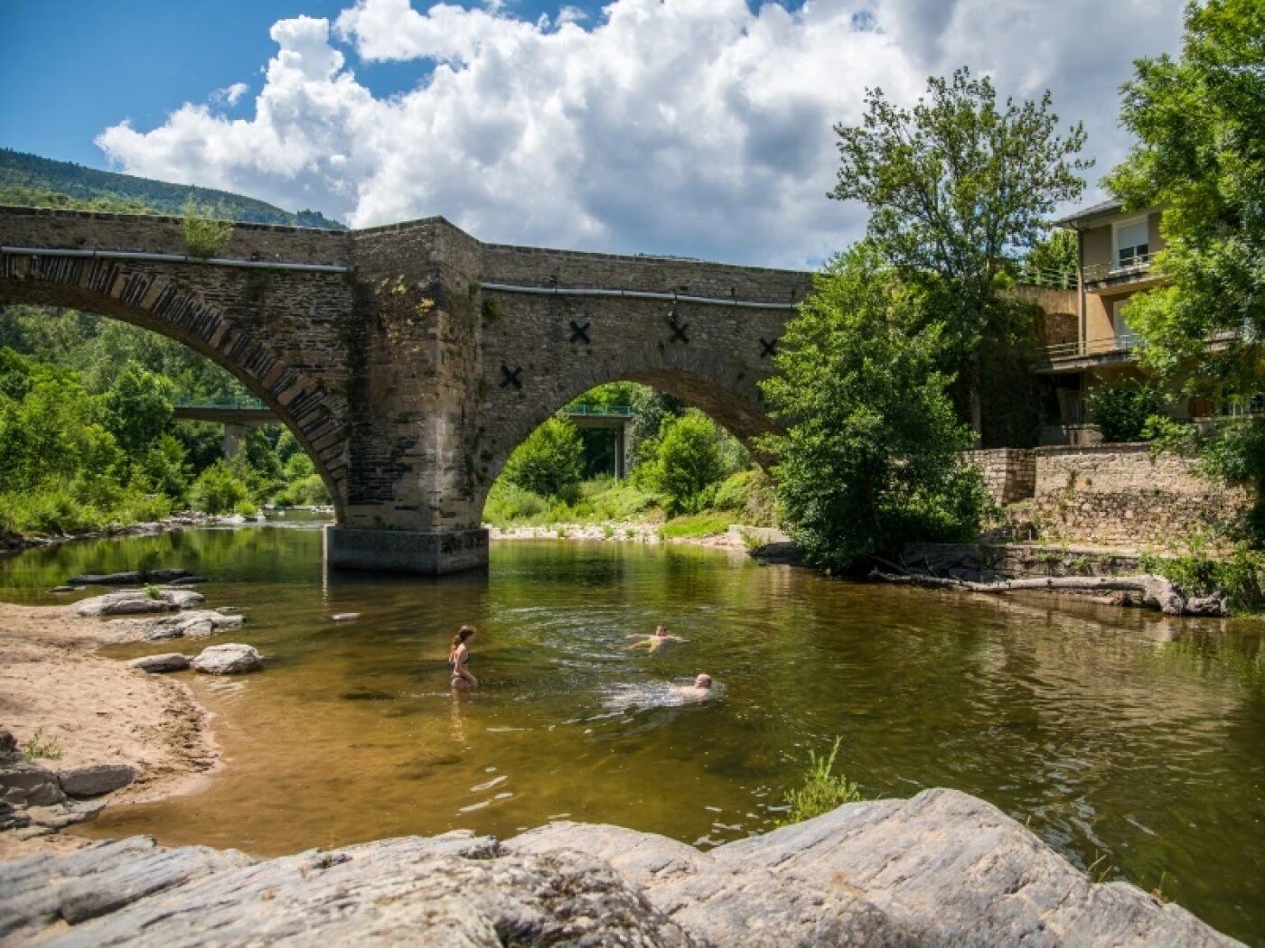 Un puente de piedra sobre un río, con una persona nadando.