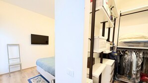 Een slaapkamer met een bed, een kleine tafel, een stoel, een televisie en een kledingkast.