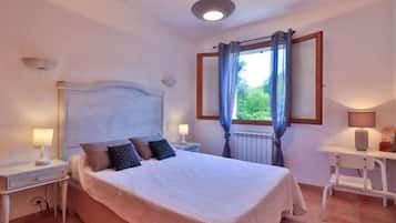 A bedroom with a bed, nightstands, a desk, and a window with curtains.