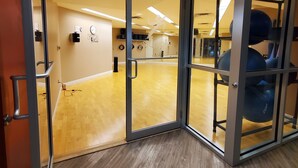 Una palestra con pareti a specchio, attrezzature per esercizi e pavimento in legno.