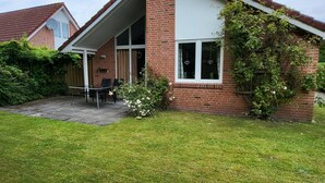 A two-story house with a brick exterior, a covered porch, and a well-maintained lawn. - Haus Teelke vacation home in an idyllic location directly on the river (Papenburg)