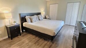A bedroom with a bed, nightstands, a dresser, and a closet. - 4BR Montego Bay Villa Near Disney (Kissimmee)