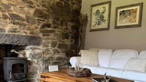 Eine Steinsäule, ein weißes Sofa, ein Holztisch und ein Kamin.