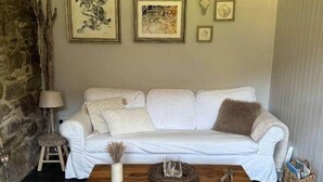 Ein Wohnzimmer mit einem weißen Sofa, einem Holztisch und gerahmten Kunstwerken an der Wand.