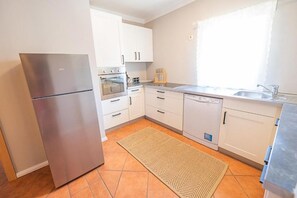 A modern kitchen with white cabinets, stainless steel appliances, and a herringbone-patterned rug.