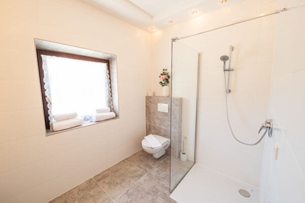 Un baño con inodoro, ducha y ventana, con toallas.