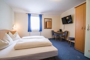 A hotel room with a bed, a desk with two chairs, a television, and a wardrobe. - Landhaus Gretl (Krumpendorf am Woerther See)