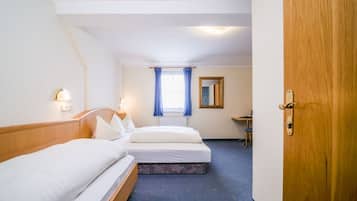 A hotel room with two beds, a desk, a chair, a window with curtains, and a door.