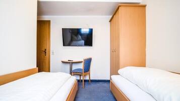 Ein Hotelzimmer mit zwei Betten, einem Fernseher an der Wand, einem Schreibtisch und einem Stuhl.