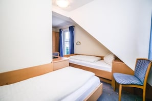 A small, triangular room with a single bed, a chair, and a desk. - Landhaus Gretl (Krumpendorf am Woerther See)