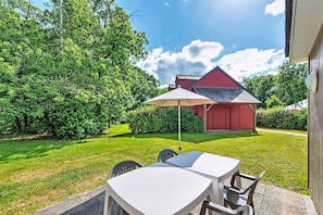 A patio with a table and chairs, a red building in the background, and a well-maintained lawn. - Cottage for Five Guests in Saumur (Saumur)