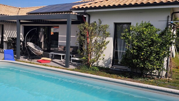 A swimming pool with lounge chairs and a covered patio area. - Spacious, bright villa ideal for a stay in Mimizan with private pool (MIMIZAN)