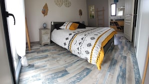 A bedroom with a bed, nightstand, and a view into the kitchen. - Spacious, bright villa ideal for a stay in Mimizan with private pool (MIMIZAN)