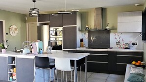 A modern kitchen with a central island, bar stools, and a dining table. - Spacious, bright villa ideal for a stay in Mimizan with private pool (MIMIZAN)
