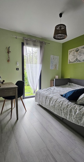 Une chambre à coucher comprenant un lit, un bureau, une chaise, une fenêtre avec des rideaux et un luminaire suspendu.