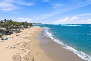Een strand met palmbomen, een zandstrand en een heldere blauwe oceaan.