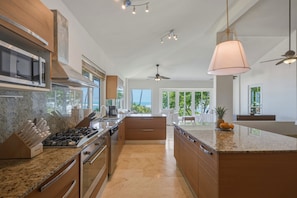 Een moderne keuken met inbouwapparatuur, een groot eiland en uitzicht op de omgeving.