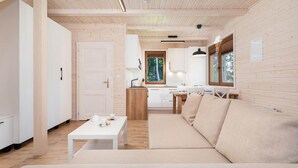 A modern interior with a wooden ceiling, a sofa, a dining table, and a kitchen area. - Comfortable Holiday Home , Summer Pool (Rewal)