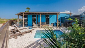 Ein modernes Haus mit Swimmingpool, Sitzgelegenheit im Freien und einer blauen Fassade.