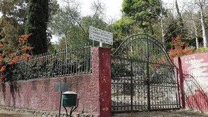 A gated entrance with a sign, a metal gate, a red wall, and a green mailbox.