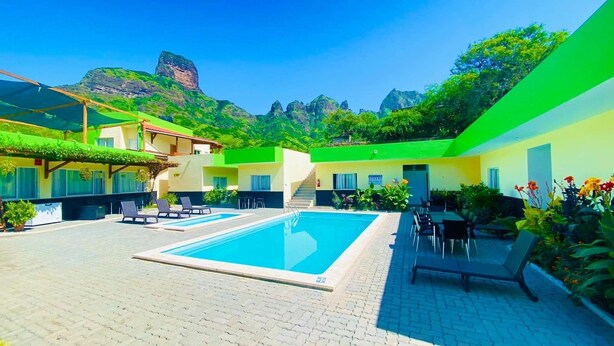 A pool area with two pools, outdoor seating, and a mountain backdrop.