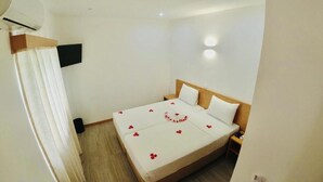 A hotel room with a bed, a TV mounted on the wall, and a wooden headboard.